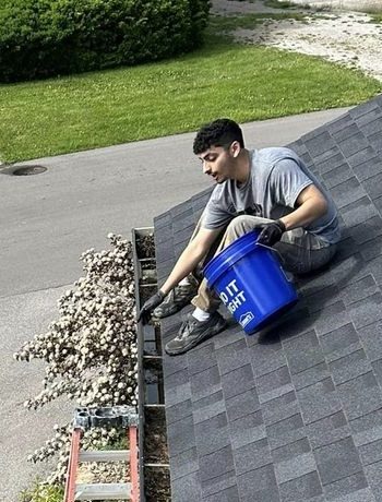 Technician removing leaves from a gutter